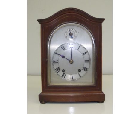 A mahogany mantle clock, arched top, with Roman numeral dial. 11 inches high.