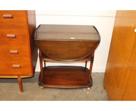 An Ercol three tier galleried tea trolley, with drop flaps raised on rounded columns and castors, 69cm wide 