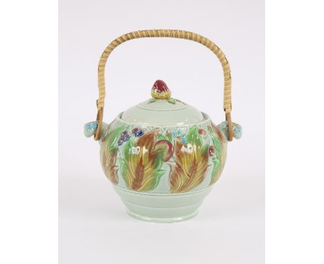 A Clarice Cliff biscuit barrel, having raised foliate decoration and fruit finial on a pale green ground with wicker handle, 