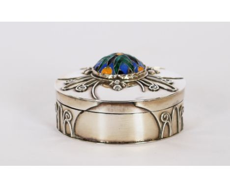 A white metal circular box and cover, central enamel boss within foliate scrolls, 5.5cm dia. 