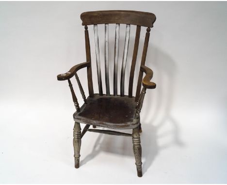 An early 20th century stick back elbow chair with solid seat and turned legs, linked by stretchers