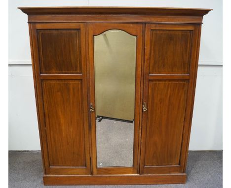 An Edwardian mahogany triple wardrobe, the central mirrored door flanked by two panelled doors, opening to reveal a shelf abo