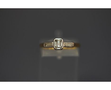 An 18 carat gold three stone diamond ring, the central step cut of approximately 0.4 carats, flanked either side by long bagu