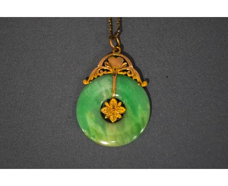 A jade pendant, of disc form, to an unmarked mount, on a chain tagged '14K', disc 2.6 cm diameter, chain 42 cm long, 6.3 g gr