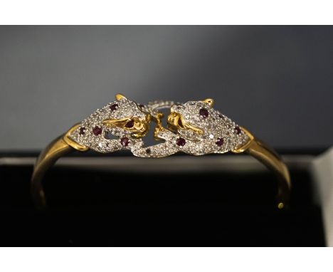 A diamond and ruby panthers bangle, stamped '9K', the confronting panthers to the frontispiece pave set with small brilliant 
