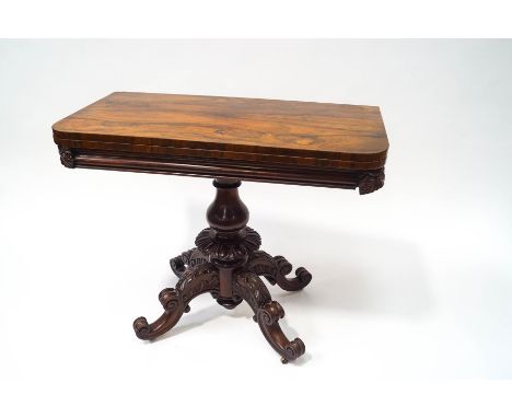 A Victorian rosewood card table with turned baluster pedestal and four carved scroll legs with brass casters, 75.5cm high x 9