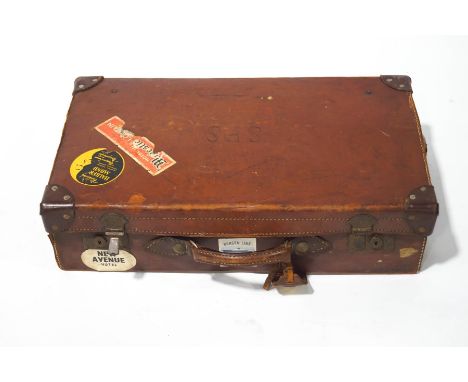 A vintage leather suitcase, with various luggage labels, 62cm wide.