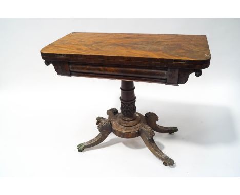 A William IV mahogany card table with leaf carved and turned pedestal on four splayed legs with brass paw terminals and caste
