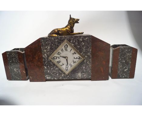 An Art Deco marble clock garniture, the eight day clock surmounted by a figure of a German Alsatian, 28cm high, and a matchin