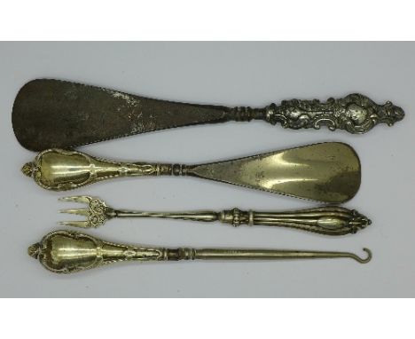 A silver handled shoe horn and matching button hook, one other silver handled shoe horn and a white metal fork