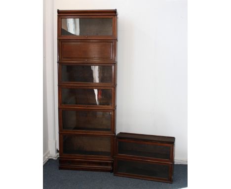 A Globe-Wernicke oak sectional graduated bookcase, the eight sections having one panelled door, drawer to the base, plinth ba