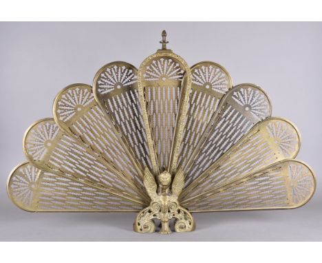 A brass peacock fan spark guard with griffin decoration, 63 cm high together with a gilt gesso pricket candlestick, 102 cm hi