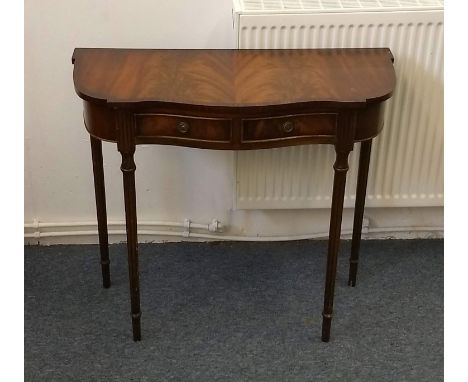 A mahogany crossbanded console table, swept outline, two short drawers, fluted tapered supports, 80 cm wide x 34 cm deep x 73