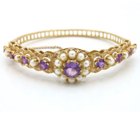 An antique ornate 9ct gold bangle set with amethyst & pearl, internal measurement 57mm x 47mm, 17.4g