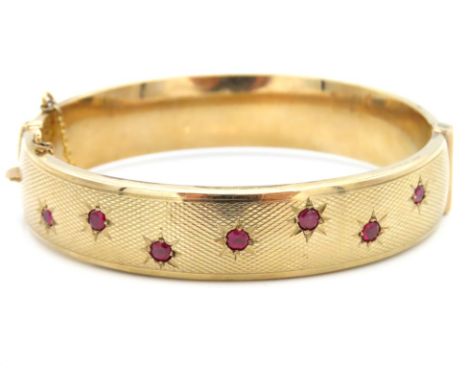 A 9ct gold bangle set with seven rubies, each approx. 3.25mm diameter, 59mm x 50mm internal dimensions, 24.9g