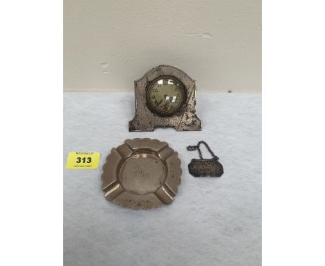 A silver engine turned bedside clock, Birmingham 1931, 3¼' high; together with a silver ashtray and silver Brandy label