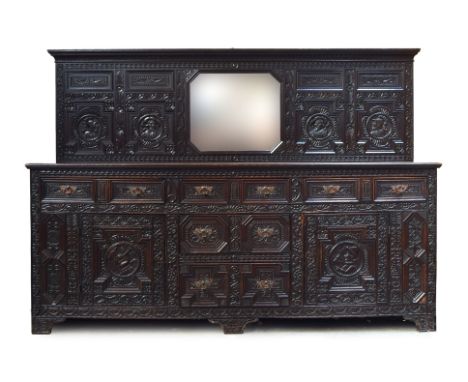 A very substantial late Victorian oak sideboard, the upstand with central mirror, the whole carved profusely in Jacobethan ta