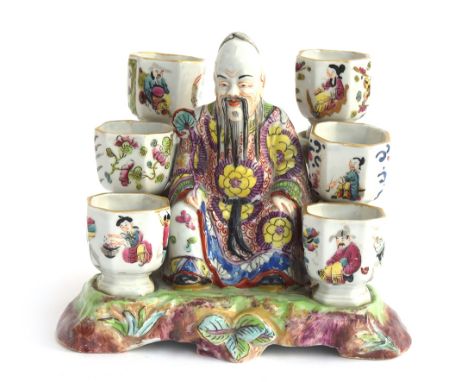 A 19th century porcelain chinoiserie figural inkwell in the form of a seated sage surrounded by six octagonal inkwells, each 