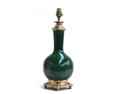 A ceramic table lamp of bottle form glazed in emerald green, mounted in white metal, incised with signature to base, 47cm hig