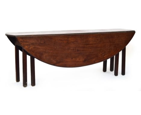 A George III mahogany wake table, the top with hinged drop leaves, on eight moulded square section legs, 210cm long, 140cm wi