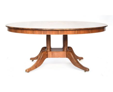 A contemporary bespoke made walnut circular dining table, on a four column base with swept legs and brass casters, 175cm diam