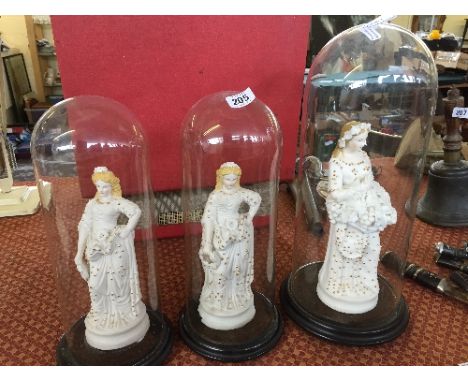 Three late 19th century Bisque china figures modelled as The Bride and Two Bridesmaids all under glass domes.