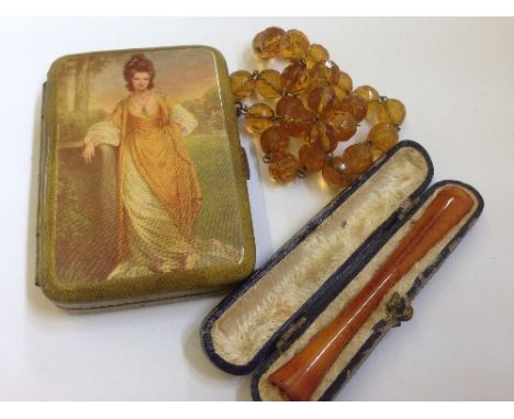 An amber style cigarette holder in original fitted case together with a glass bead necklace and a Bakelite cigarette case.