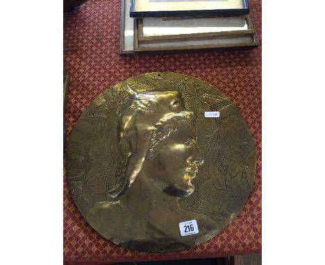 An arts and crafts brass circular plaque decoarted with a portrait of a Greek athlete.