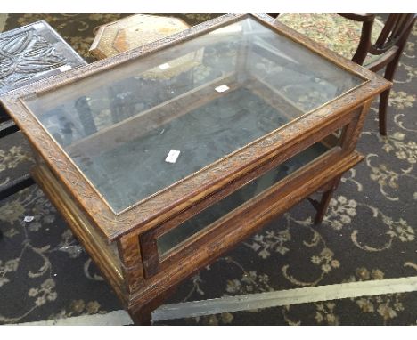 A carved oak display case with lift-off glazed top and drop glass panelled side, resting on separate carved oak base, reputed
