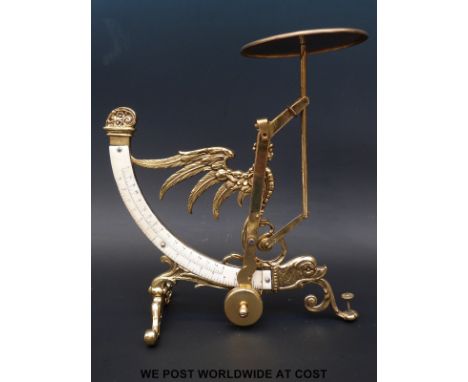 A brass postage scale with curved double scale, the body formed as a winged mythical creature with dolphins head below 