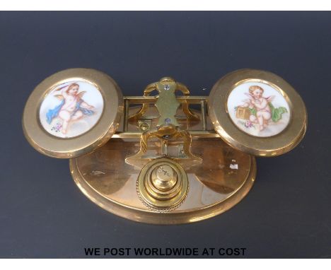 A set of brass postage scales with ceramic plaques of cherubs to the pans and stack of weights to the front 