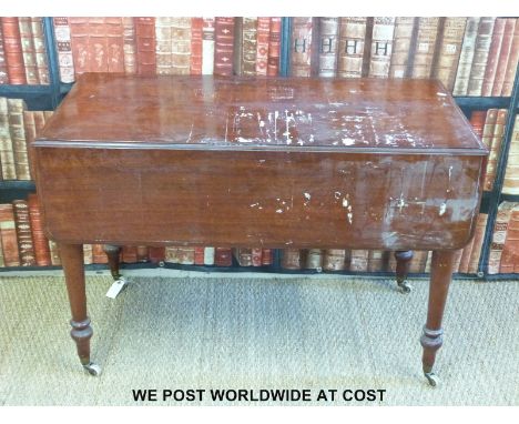 A mahogany drop leaf table raised on ceramic castors (H72 x W106 x D107cm)