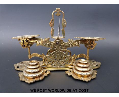 A set of pierced and cast brass postage scales with two stacks of weights to front 