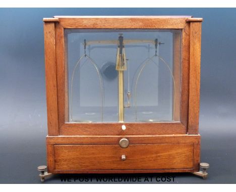 A set of small cased laboratory scales with drawer below containing various weights including grains etc 