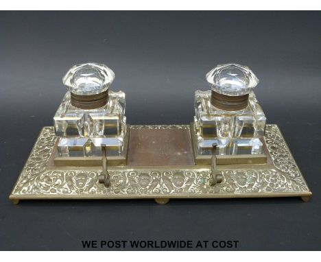 A Victorian brass inkwell with embossed decoration and cut glass inkwells