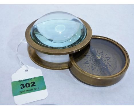 A brass compass under a bullseye lens. Of recent manufacture