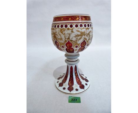 A 19th century Bohemian ruby and milk glass overlaid goblet decorated with arabesques and gilded with vine fruits. 10'' high