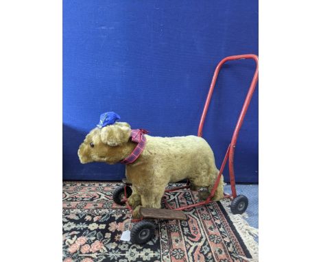 A 1940's Tri-ang, Pedigree push along teddy bear with a red painted metal frame, wooden foot rests and rubber wheels, 37cm hi