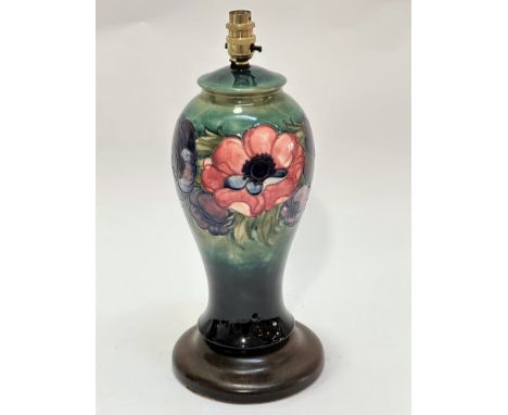 A Moorcroft pottery baluster vase lamp with green ground and tube lined anemone design raised on hardwood circular moulded ba