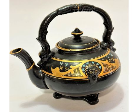 A pottery black glazed and gilded teapot with lion mask moulding to border with Forget Me Nots to top and serpent scroll hand