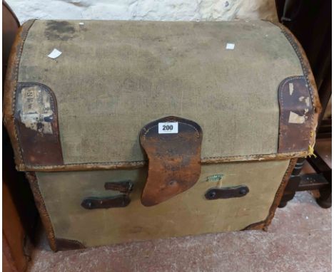 A vintage canvas dome-top travelling trunk with leather bound corners, strapping and flanking handles, the interior with orig