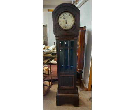 A vintage stained wood longcase clock with glazed trunk door, visible pendulum and spring driven eight day chiming movement