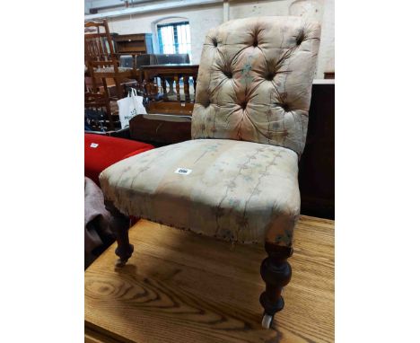 A Victorian low boudoir chair with remains of button back upholstery, set on turned front legs with white porcelain casters -