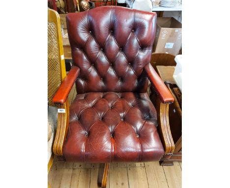 A late 20th Century swivel elbow chair with studded and button backed red leather upholstery, set on five swept legs and cast