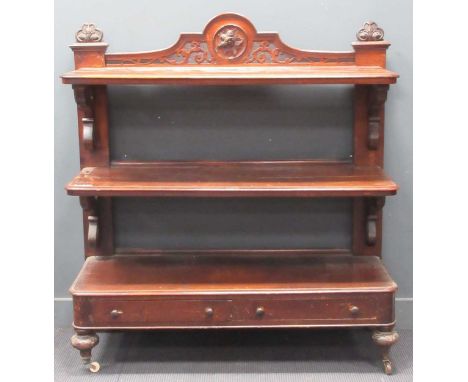 A Victorian three tier buffet with overscrolled foliate shelf supports and blind cut carved crest to the top of the back, set