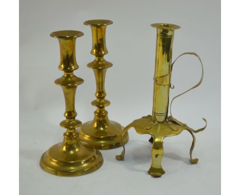 An Arts & Crafts brass candlestick with scrolling strap handle, on three raised feet, 28 cm high to/w a 19th century pair of 