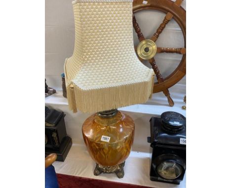 A tall brass lamp with a large orange glass font with shade 