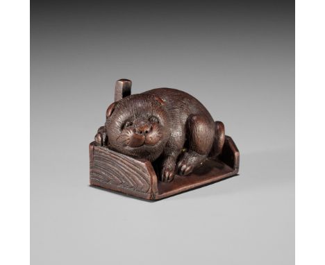 KOKEI: A WOOD NETSUKE OF A PUPPY INSIDE A DUSTPANBy Kokei, signed Kokei 虎溪Japan, Kuwana, Ise Province, 19th century, Edo peri