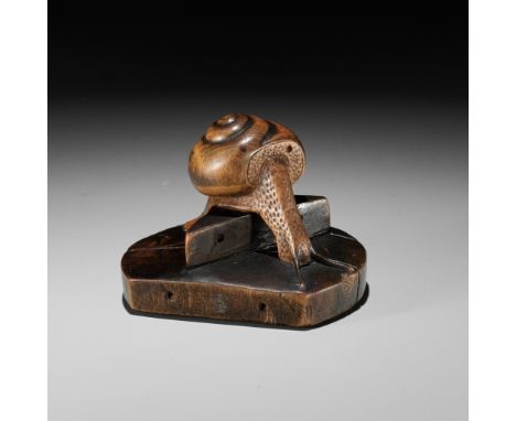 TOMOSHIGE: A RARE WOOD NETSUKE OF A SNAIL ON A WELL BUCKET COVERBy Gyokuryusai Tomoshige, signed Tomoshige 友重Japan, Nagoya, c