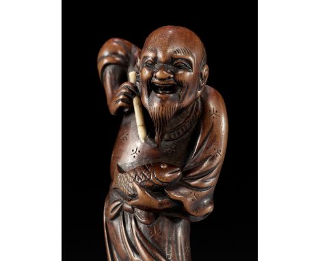 AN UNUSUAL WOOD NETSUKE DEPICTING KINKO SENNIN WITH A BRUSH AND FISHUnsigned Japan, late 18th to early 19th century, Edo peri